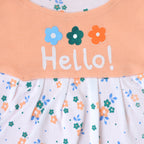 Children's dress with floral pattern and 'Hello!' text on a peach background