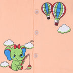 Children's clothing with a green elephant and hot air balloons design on a peach background.